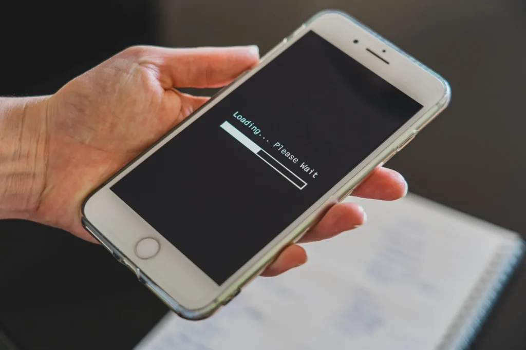 Hand houdt een smartphone vast waarop een laadbalk met de tekst Loading staat