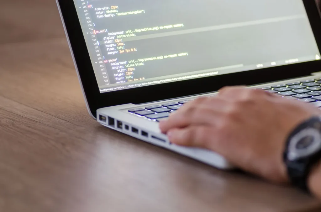 Hand op het toetsenbord van een laptop met CSS-code van een website op het scherm